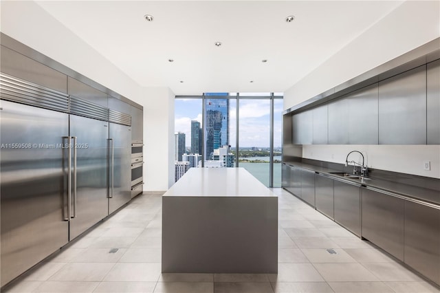 kitchen with dark countertops, a wall of windows, stainless steel appliances, modern cabinets, and a sink