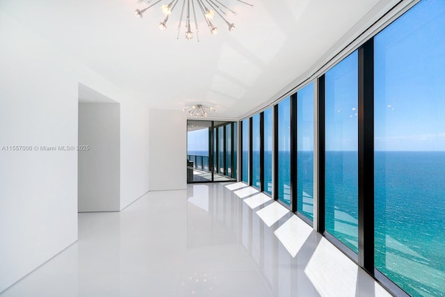 corridor with tile patterned flooring, a notable chandelier, expansive windows, and a water view