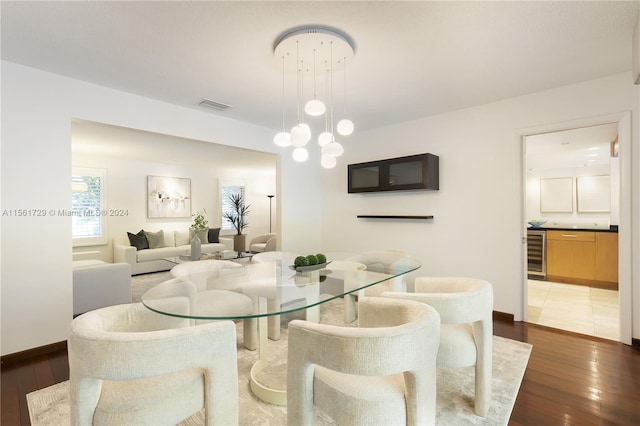 dining room with a notable chandelier, dark hardwood / wood-style flooring, and beverage cooler