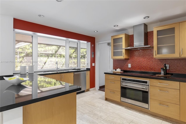 kitchen with backsplash, wall chimney range hood, sink, light brown cabinetry, and stainless steel appliances