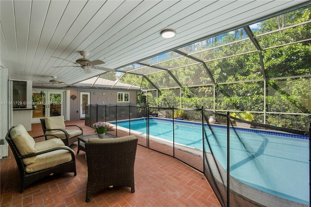 view of swimming pool featuring outdoor lounge area, ceiling fan, a patio, and glass enclosure