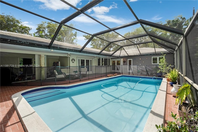 view of pool with glass enclosure, ceiling fan, a patio area, and an outdoor living space