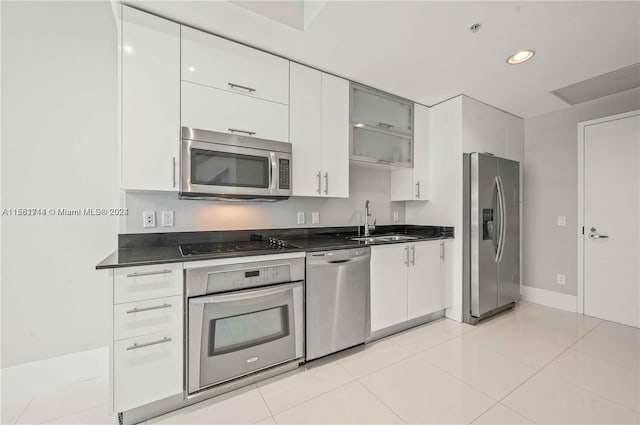 kitchen featuring stainless steel appliances, white cabinetry, light tile floors, and sink