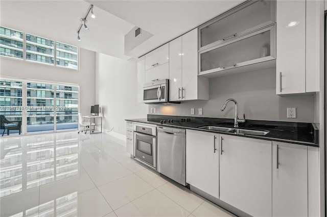 kitchen featuring sink, light tile floors, appliances with stainless steel finishes, white cabinets, and track lighting