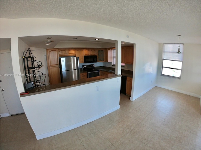 kitchen with light tile flooring, decorative light fixtures, stove, and stainless steel refrigerator