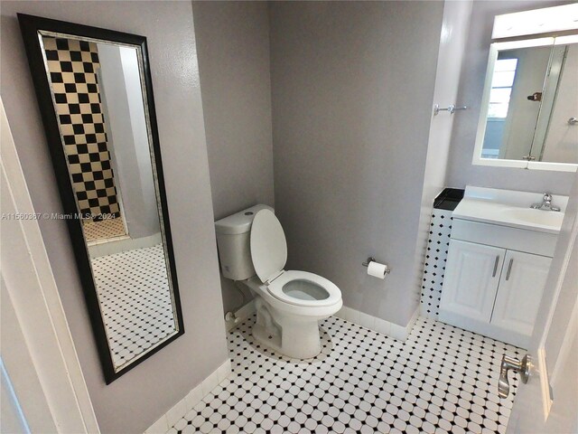 bathroom featuring a shower, toilet, tile flooring, and vanity