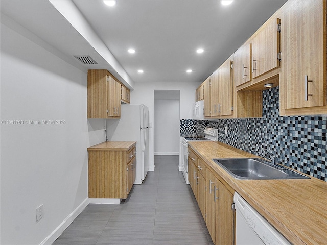 kitchen with backsplash, white appliances, light tile flooring, and sink