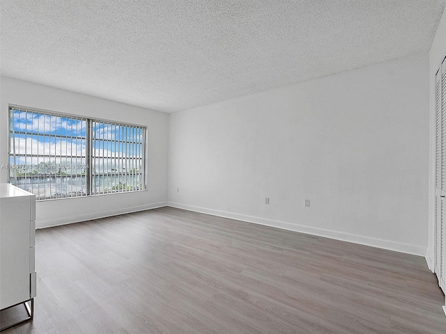 empty room with hardwood / wood-style floors, a textured ceiling, and a water view