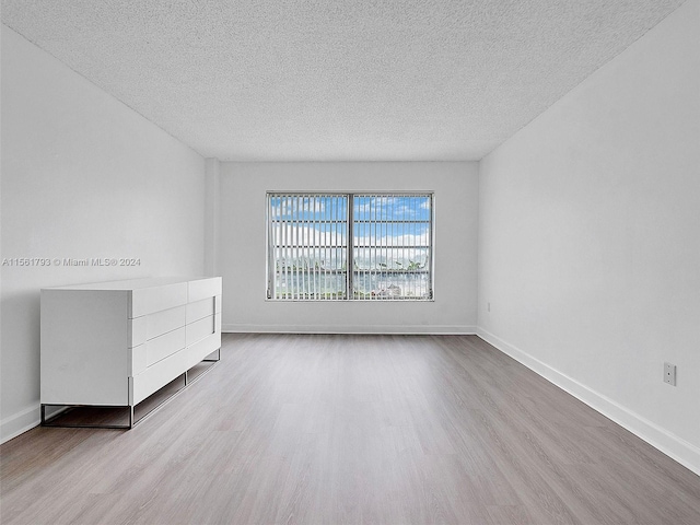 empty room with light hardwood / wood-style flooring and a textured ceiling