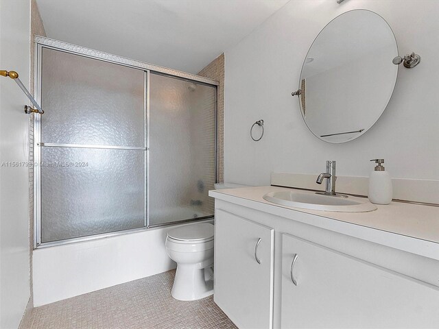 full bathroom featuring tile floors, combined bath / shower with glass door, toilet, and vanity