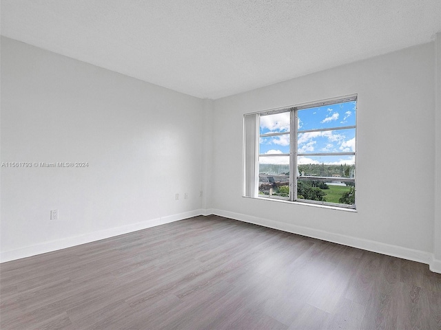 empty room with dark wood-type flooring and a textured ceiling