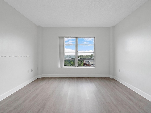 unfurnished room featuring a textured ceiling and light hardwood / wood-style flooring