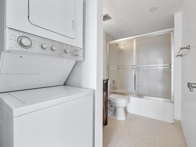 clothes washing area featuring stacked washing maching and dryer and tile floors