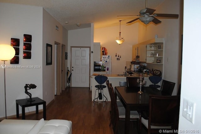 dining room with lofted ceiling, dark wood-type flooring, ceiling fan, sink, and a textured ceiling