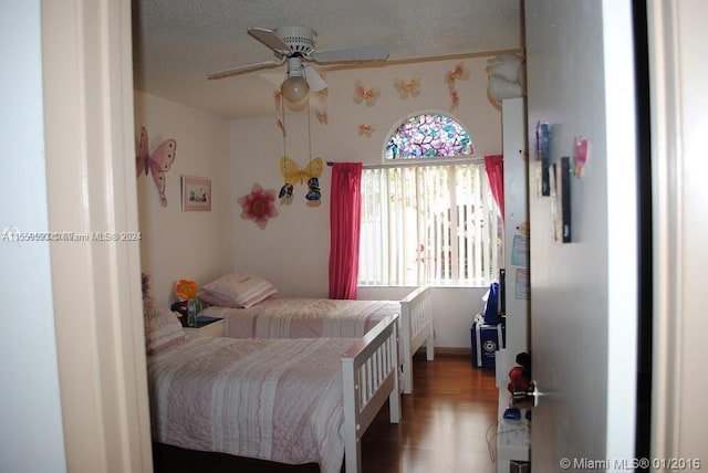 bedroom with a textured ceiling, dark hardwood / wood-style floors, and ceiling fan