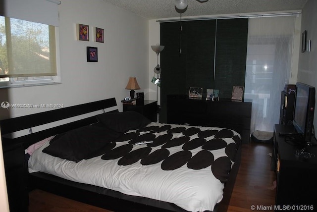 bedroom with dark hardwood / wood-style floors and a textured ceiling