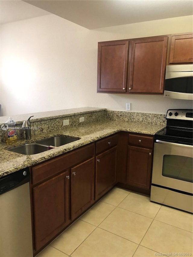 kitchen with sink, light stone counters, light tile flooring, and stainless steel appliances