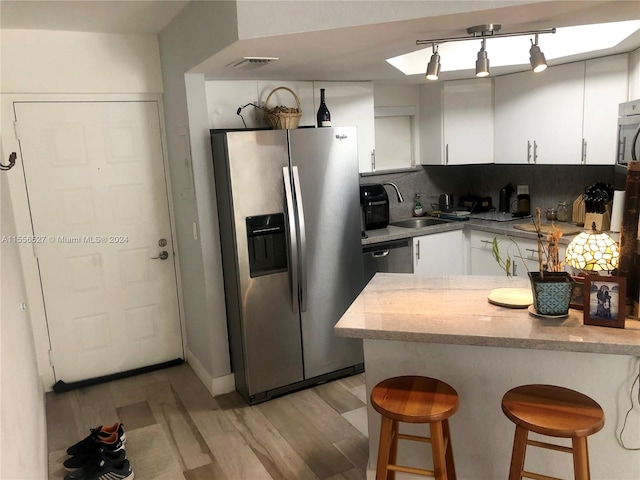 kitchen featuring backsplash, white cabinetry, a breakfast bar, and stainless steel appliances