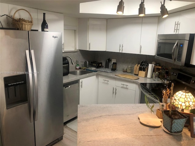 kitchen with appliances with stainless steel finishes, white cabinets, light hardwood / wood-style flooring, backsplash, and sink