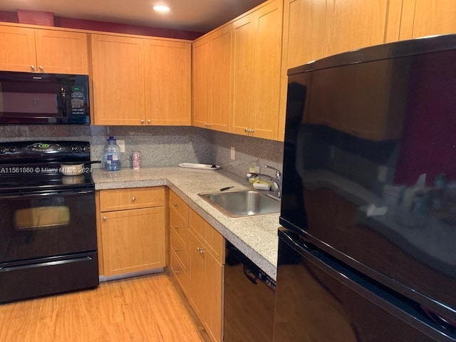 kitchen with backsplash, light hardwood / wood-style flooring, black appliances, and sink