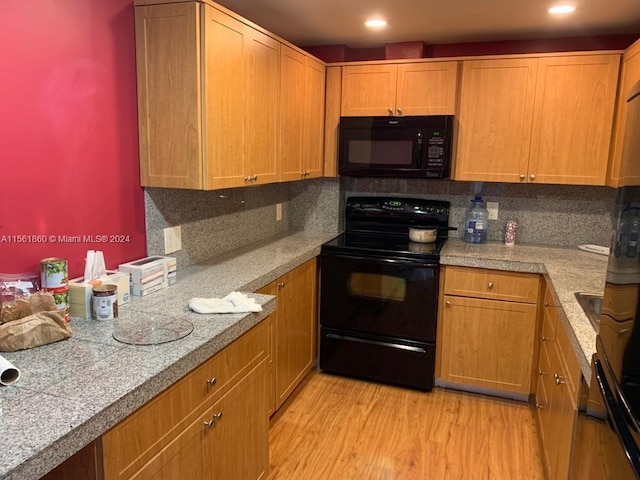 kitchen with backsplash, light hardwood / wood-style flooring, and black appliances