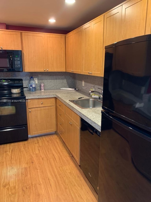 kitchen with backsplash, light wood-type flooring, black appliances, and sink