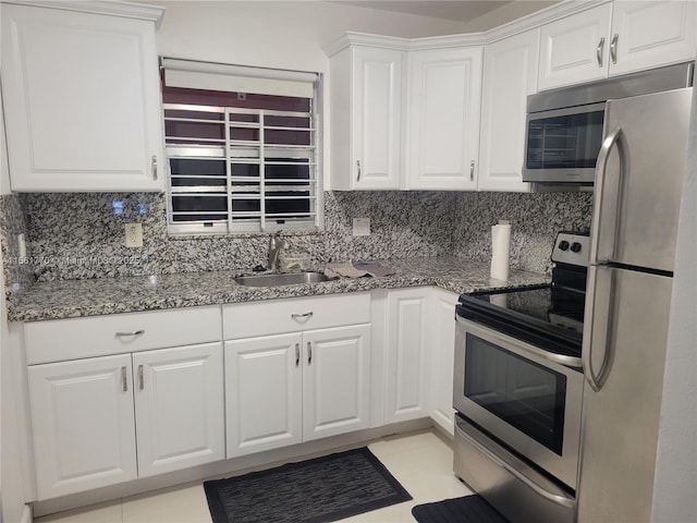 kitchen featuring stainless steel appliances, backsplash, a sink, and white cabinetry