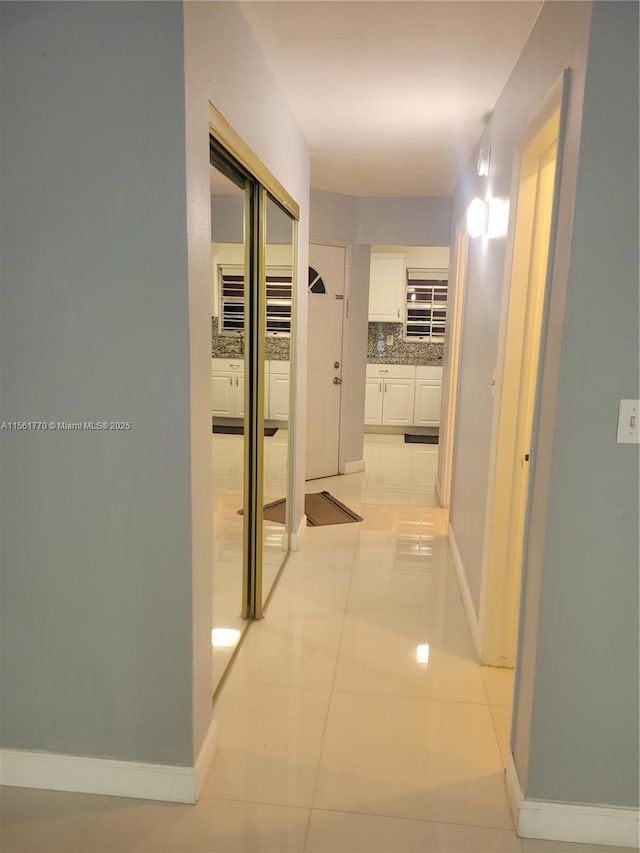 corridor featuring light tile patterned flooring and baseboards