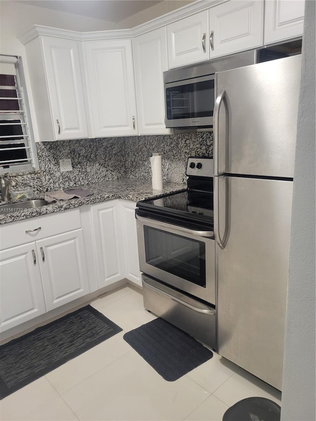 kitchen featuring white cabinetry, stainless steel appliances, backsplash, and light tile patterned flooring