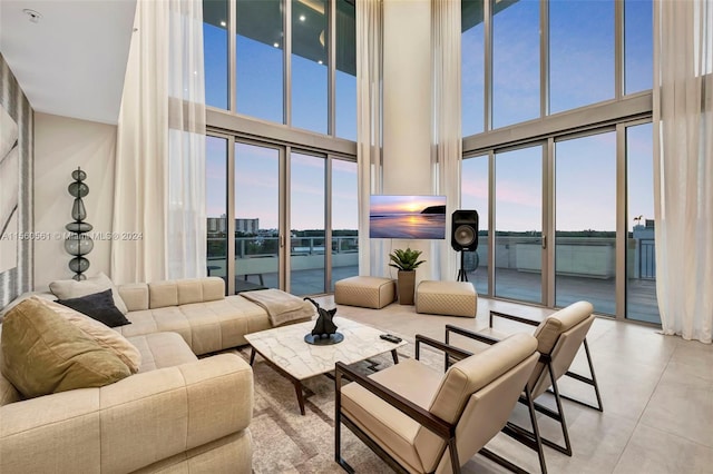 tiled living room featuring a healthy amount of sunlight, a water view, and a towering ceiling