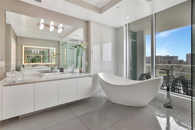 bathroom with a wall of windows, a raised ceiling, tile floors, a washtub, and vanity