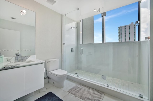 bathroom with tile floors, a shower with shower door, vanity, and toilet