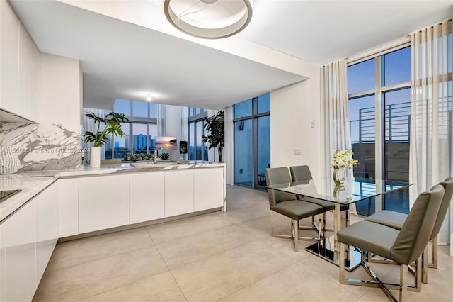 kitchen with sink, white cabinets, light tile flooring, and expansive windows