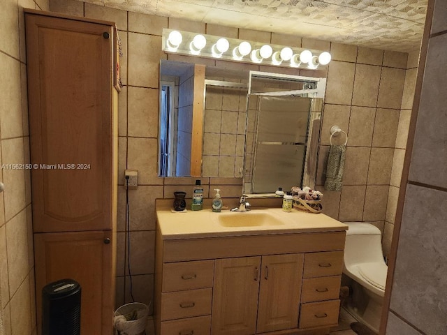 bathroom featuring vanity, toilet, and tile walls