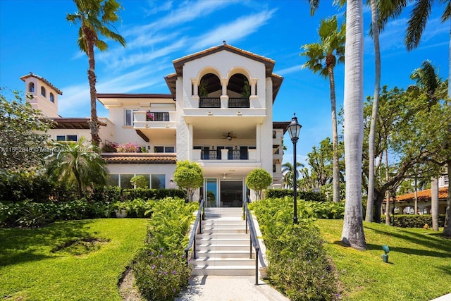 mediterranean / spanish-style home featuring ceiling fan, a balcony, and a front lawn