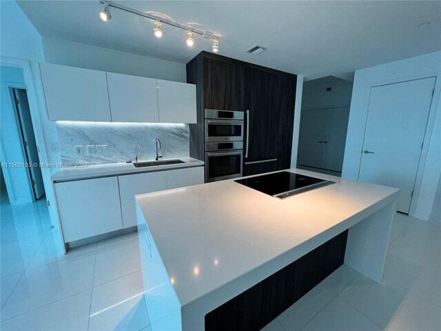 kitchen featuring white cabinets, stainless steel double oven, black electric cooktop, and sink