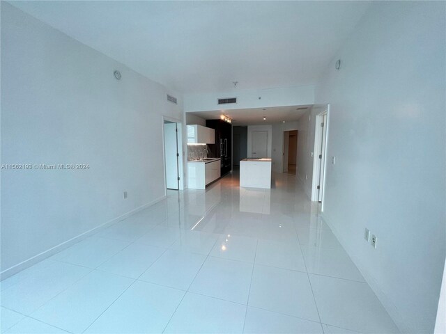 corridor featuring sink and light tile floors