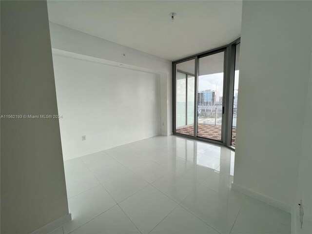 tiled empty room featuring a wall of windows