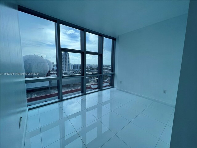 spare room featuring expansive windows and light tile floors