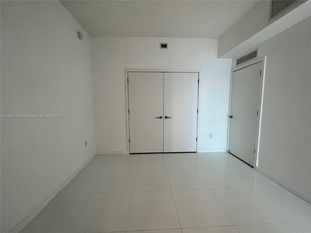 unfurnished bedroom featuring a closet and light tile floors