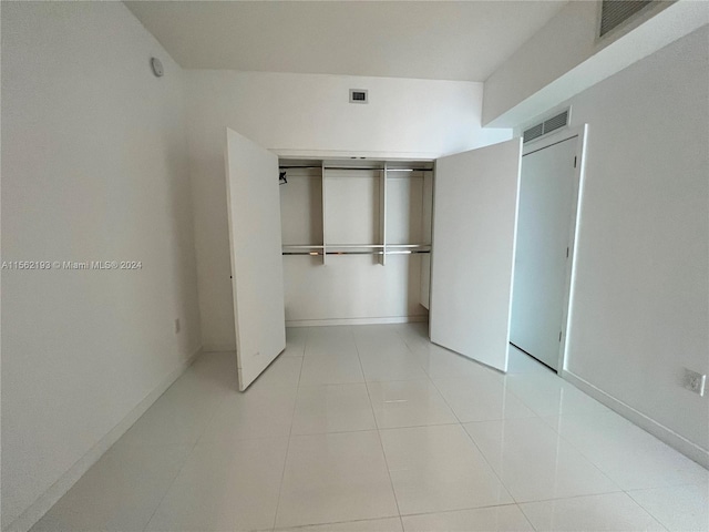 unfurnished bedroom featuring a closet and light tile floors