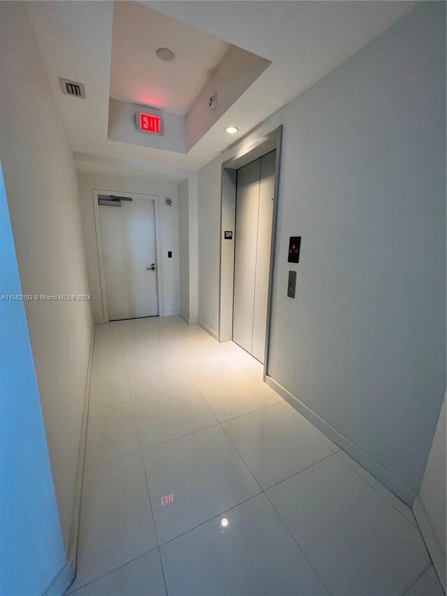 hall with light tile floors and elevator