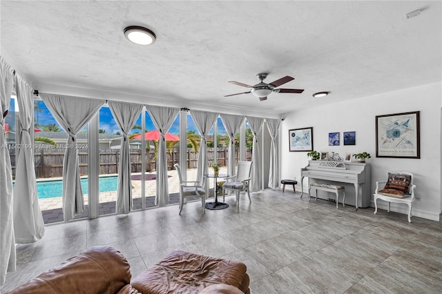 living room featuring a textured ceiling, ceiling fan, and light tile flooring