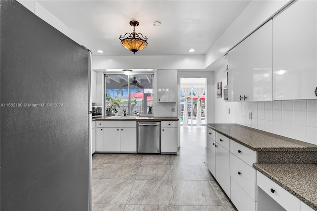 kitchen featuring stainless steel dishwasher, pendant lighting, light tile flooring, backsplash, and white cabinets