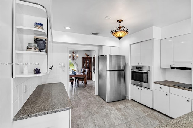 kitchen with hanging light fixtures, stainless steel appliances, backsplash, white cabinetry, and a chandelier