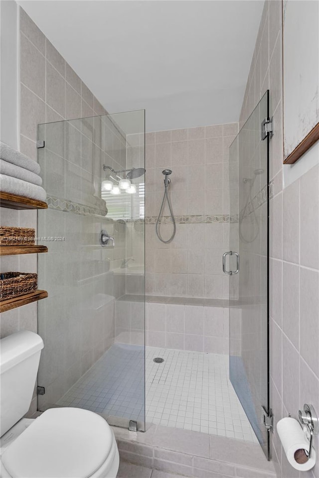 bathroom with a shower with shower door, tile walls, and toilet