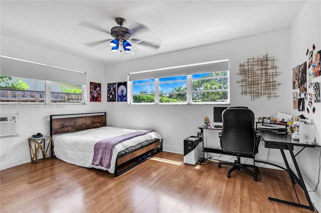 bedroom featuring an AC wall unit, ceiling fan, and light hardwood / wood-style flooring