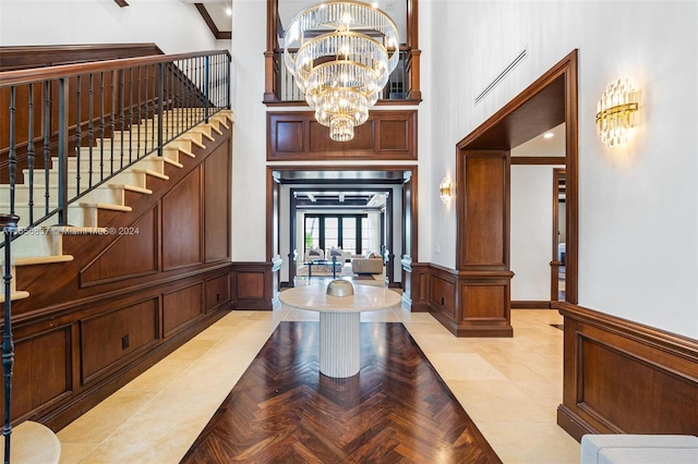 foyer entrance with a chandelier, light parquet floors, and a high ceiling