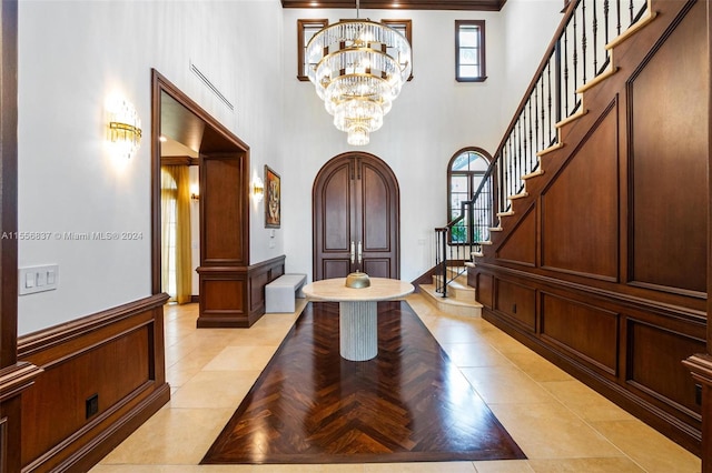 tiled foyer featuring a chandelier, a towering ceiling, and ornamental molding