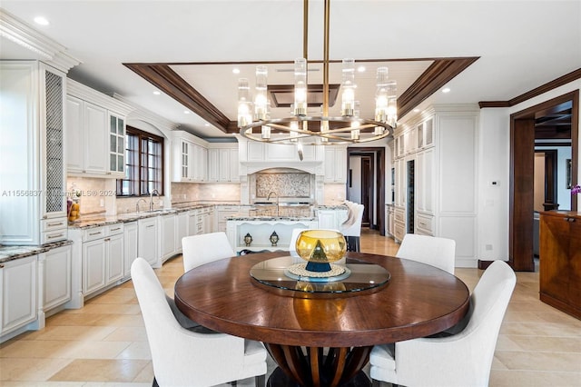 tiled dining space featuring ornamental molding, a notable chandelier, sink, and a tray ceiling